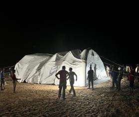 MSF aid workers with an inflatable tent hospital lit up in the night in Chad