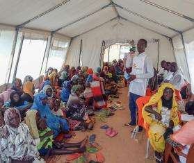 A crowd of Sudanese refugees sit inside a tent while awaiting medical care from Doctors Without Borders staff. 