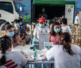 An MSF team surrounded by patients is working around a table surrounded by tuberculosis medication in Tondo, Manila.