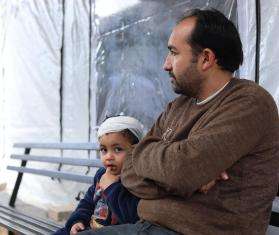 A Palestinian father and child sit outside an MSF medical point in Gaza.