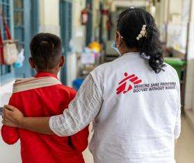 An MSF walks with their arm around an HIV patient in India.