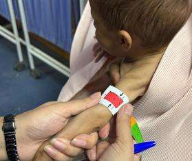 An MSF nurse measures a child's mid-upper arm circumference (MUAC) to assess a baby during triage at MSF's outpatient therapeutic feeding center in Kandahar.