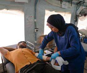 A physiotherapist adjusts the fit of a patient's splint at Al-Zawayda field hospital.