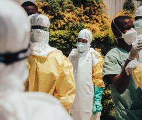 Colleagues help one another into their personal protective equipment (PPE) before decontaminating homes in Bunia, Ituri province, DR Congo.