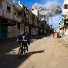 A person rides a bike down a street left in ruins in Rafah, Gaza.