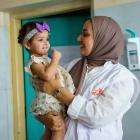 An MSF staff member holds Zahraa, a young child receiving follow-up care at Al-Mahdi Health Center in Sadr City, Baghdad.